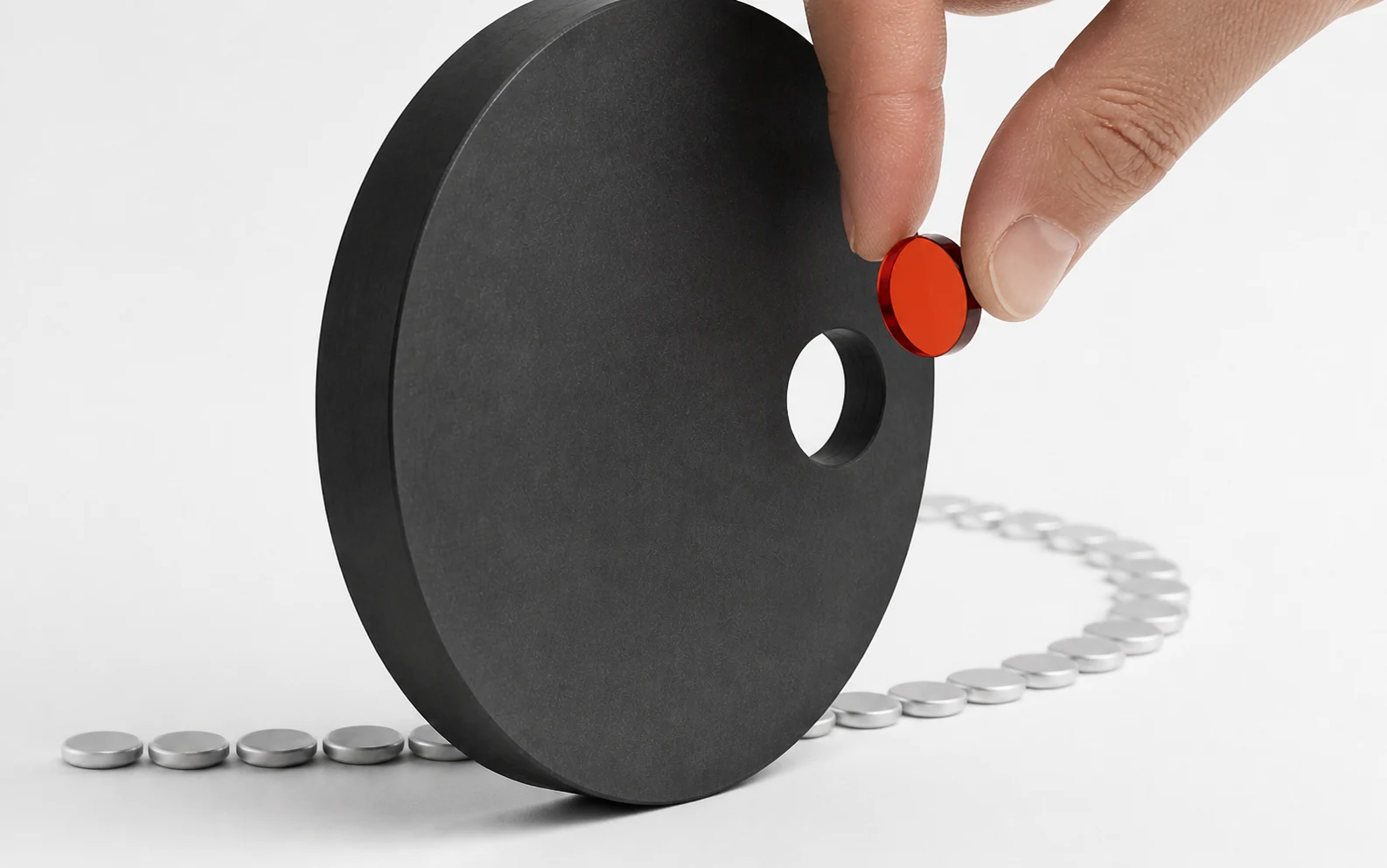 A human hand lifts one vermilion exception from an ordered aluminium flow at a carbon aperture.